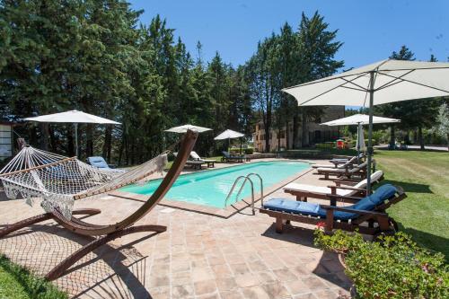 a swimming pool with chairs and umbrellas and a swing at Podere Caldaruccio La Pineta in Bosco