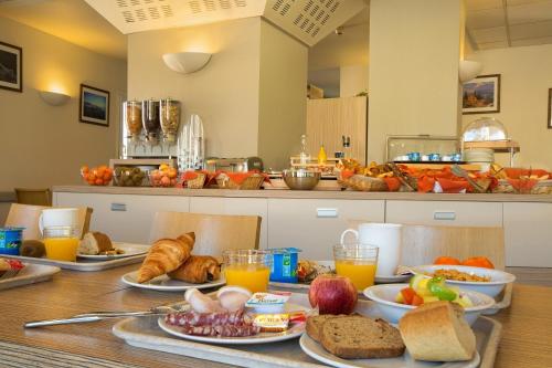 uma mesa coberta com pratos de comida e sumo de laranja em Hotel Espace Cite em Carcassonne