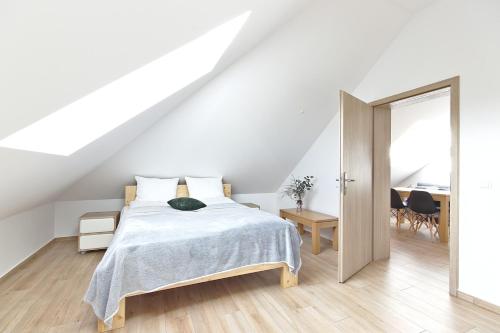 a white bedroom with a bed and a table at Apartamenty Forma Tatrica in Zakopane