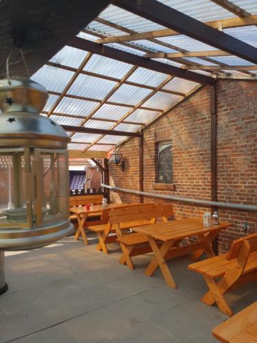 un groupe de tables de pique-nique dans un bâtiment en briques dans l'établissement Hotel & Restaurant Gulfhof, à Emden