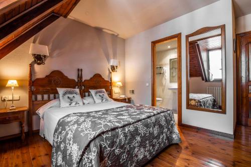 a bedroom with a large bed and a mirror at Hotel Fonfreda in Vielha