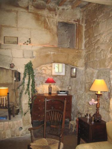 Zimmer mit einer Steinmauer, einem Schreibtisch und einer Lampe in der Unterkunft Grand Argence in Fourques
