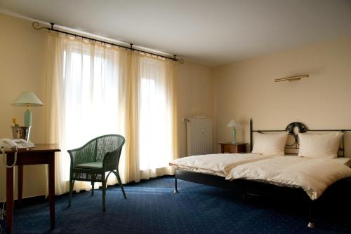 a bedroom with a bed and a chair and a desk at Landhotel Schuff in Kindsbach