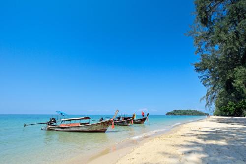 two boats sitting in the water on a beach at JR Place in Klong Muang Beach