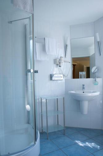 a white bathroom with a shower and a sink at Landhotel Schuff in Kindsbach