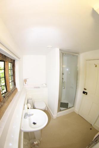 La salle de bains est pourvue d'un lavabo blanc et d'une douche. dans l'établissement FSC Flatford Mill Hostel, à East Bergholt