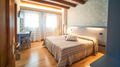 a bedroom with a bed and a desk and a window at Agriturismo Roccat in Valdobbiadene