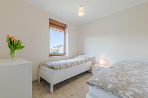 a white bedroom with a bed and a window at Nadmorskie Zacisze in Dębina