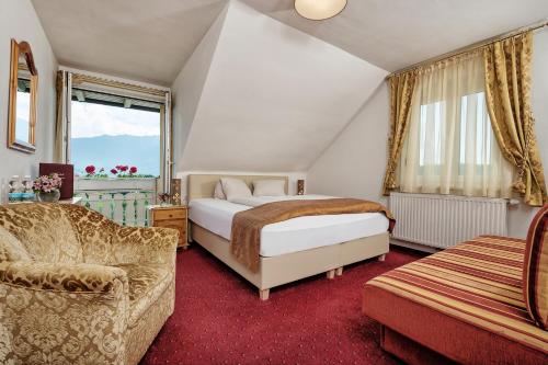 a bedroom with a bed and a couch and a chair at Hotel-Pension Melcher in Drobollach am Faaker See