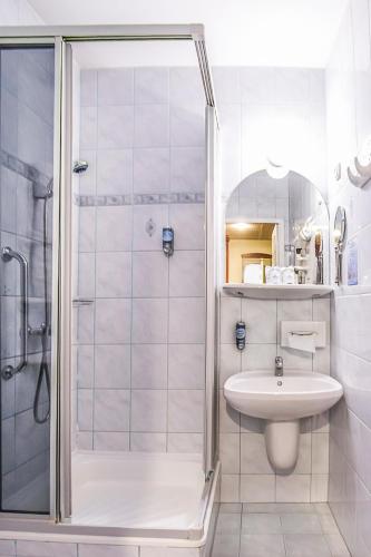 a white bathroom with a sink and a shower at Hotel Silver in Hajdúszoboszló