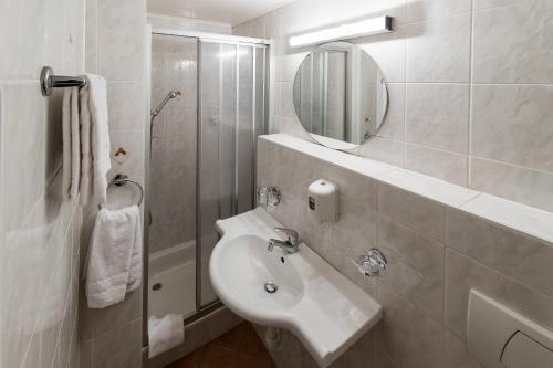 a white bathroom with a sink and a mirror at Hotel de la Place in Vevey