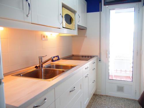 uma cozinha com um lavatório e um micro-ondas em La Baie 36 em Roses