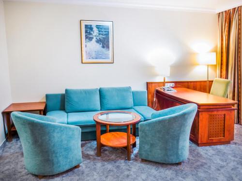 a hotel room with a couch and chairs and a table at Hotel Silver in Hajdúszoboszló