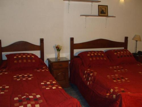 a bedroom with two beds with red comforter at Derby Home Hotel in Buenos Aires
