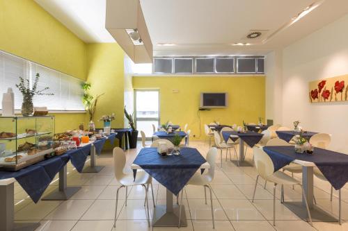a dining room with blue tables and white chairs at Silver Hotel in Matino