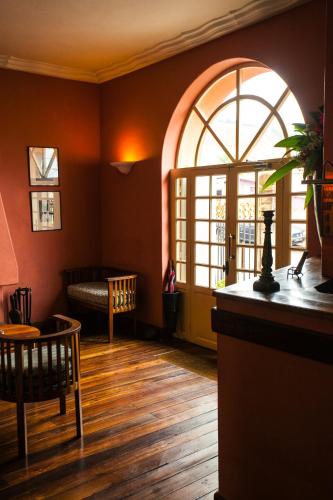 a living room with a large arched window and wooden floors at Tsara Guest House in Fianarantsoa