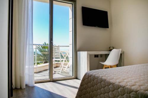 Un dormitorio con una cama y vista a un balcón. en Hotel Boutique Aroma de Mar, en Chiclana de la Frontera