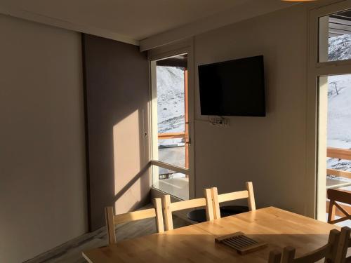 ein Esszimmer mit einem Tisch, einem TV und einem Fenster in der Unterkunft Gite Bel Air La Mongie in La Mongie
