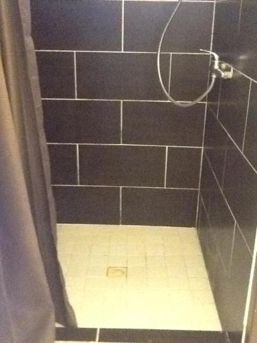 La salle de bains est pourvue d'une douche carrelée de noir et de carrelage. dans l'établissement Studio 03 vue mer Orient Bay, à La Baie-Orientale