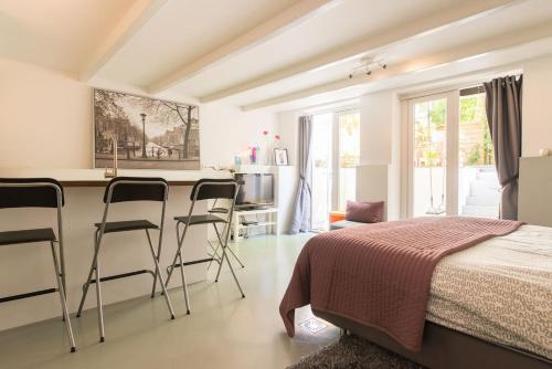 a bedroom with a bed and a kitchen with stools at Quiet apartment for 4 at park in center in Amsterdam