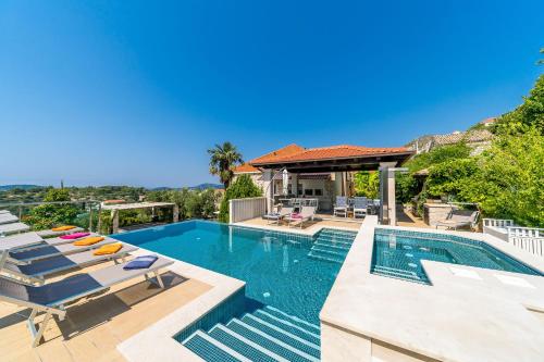 a swimming pool with lounge chairs and a house at Villa La Vagabonda in Orasac