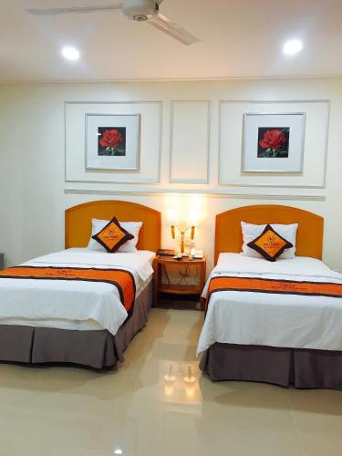 a hotel room with two beds and a night stand at Khách sạn SAO NAM in Cao Lãnh