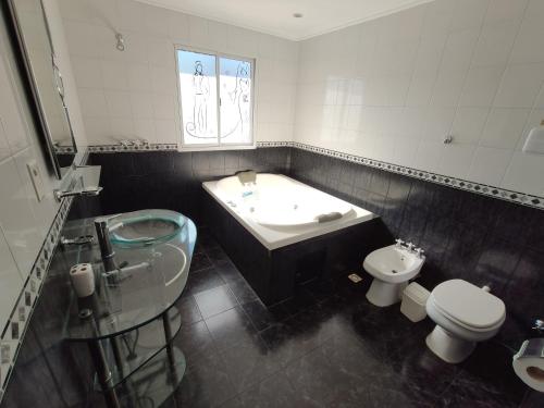 een badkamer met een wastafel, een bad en een toilet bij Hotel Amatista in Wanda