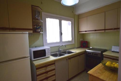 une cuisine avec un évier et un micro-ondes dans l'établissement APARTAMENTO PLAYA ARENAL, Jávea-Xàbia, à Jávea