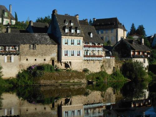 un groupe de bâtiments assis à côté d'une masse d'eau dans l'établissement Gite Clara, à Bassignac-le-Haut