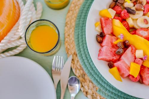 a plate of fruit and a bowl of juice at Mulubinba SeaHouse in Olhão