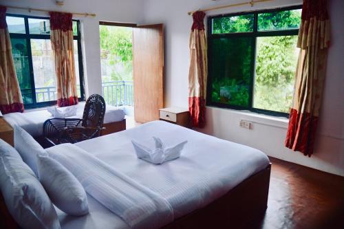 a bedroom with a large white bed with windows at Pokhara Star Inn Pvt Ltd in Pokhara