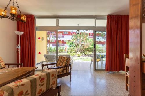 un soggiorno con tende rosse, tavolo e sedie di Apartamentos Melusina en Playa del Inglés al lado de la playa y las Dunas de Maspalomas a Playa del Ingles