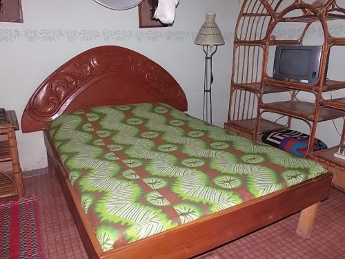 a bed with a green comforter and a television at Couleur Café in Kafountine