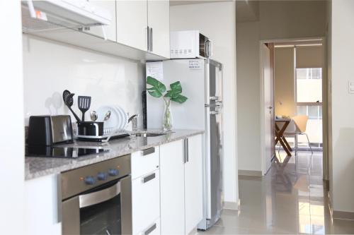 a kitchen with white cabinets and a stainless steel refrigerator at The Point Casa Edificio Boutique in San Miguel de Tucumán