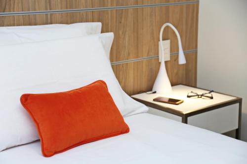 a bed with a orange pillow and a side table at The Point Casa Edificio Boutique in San Miguel de Tucumán