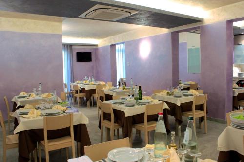 un restaurant avec des tables et des chaises blanches et des murs violets dans l'établissement Hotel Mario, à San Benedetto del Tronto