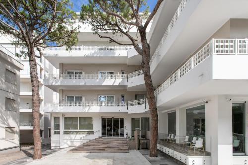einen Blick nach außen auf ein weißes Gebäude mit Bäumen in der Unterkunft Hotel Greif in Lido di Jesolo