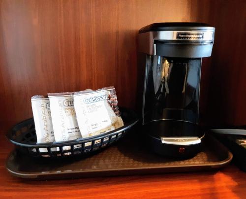 a coffee maker and a basket of coffee packets at Bay Motel in Green Bay
