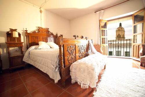 1 dormitorio con cama de madera y silla en Palacete Magistral Domínguez habitaciones, en Guadix