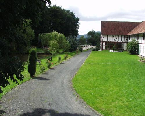 a gravel road next to a building and a grass field at Gut Dankerode in Dankerode