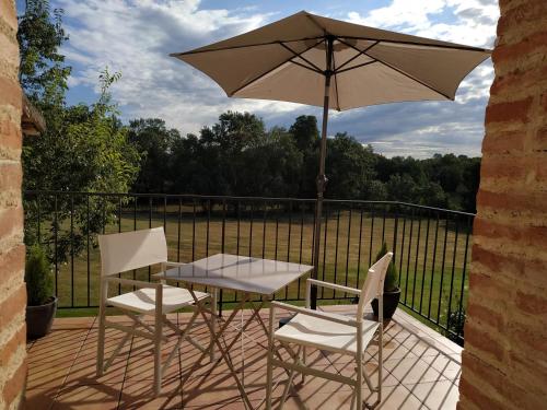 a table and two chairs and an umbrella on a deck at Bastide De Luzert in Labastide-de-Lévis