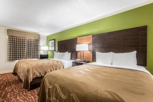 two beds in a hotel room with green walls at Quality Inn Forrest City I-40 in Forrest City