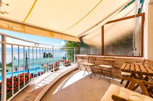 a balcony with a table and chairs and a large window at Vila Bisera in Ohrid