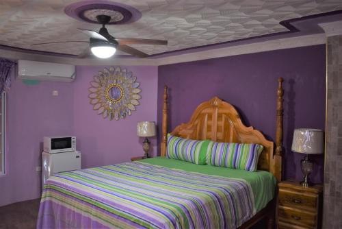 a bedroom with a bed with purple walls and a ceiling at Haven View Villa & Spa in Bluefields