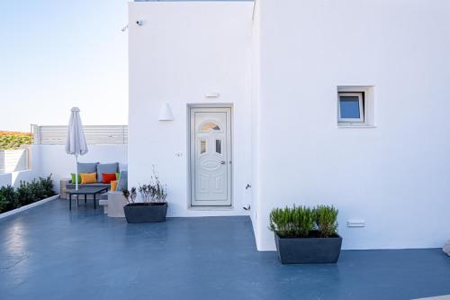 a white room with potted plants and a door at Santoterra Antigua Suites in Karterados