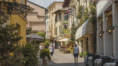 a group of people walking down a street with buildings at Hotel Du Lac Gardone Riviera in Gardone Riviera