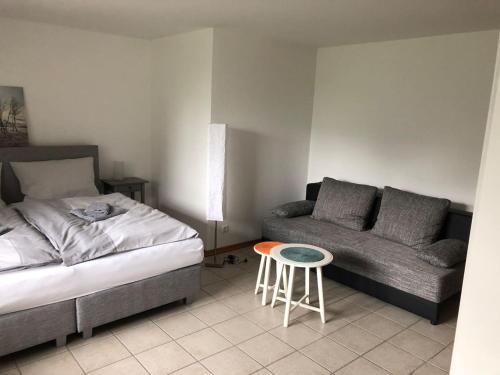 a bedroom with a bed and a stool and a couch at Wein Lodge Durbach - Schlossblick in Durbach