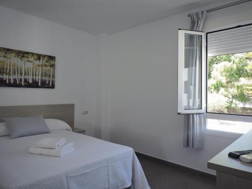 a white bedroom with a bed and a window at Hostal Delia in Alora