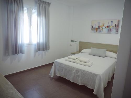 a white bedroom with a bed with two towels on it at Hostal Delia in Alora