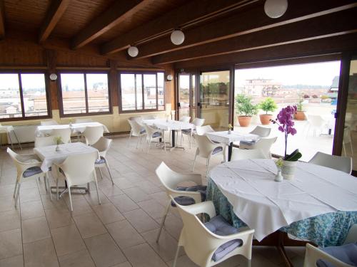 un restaurant avec des tables blanches, des chaises et des fenêtres dans l'établissement Hotel Tessarin, à Taglio di Po